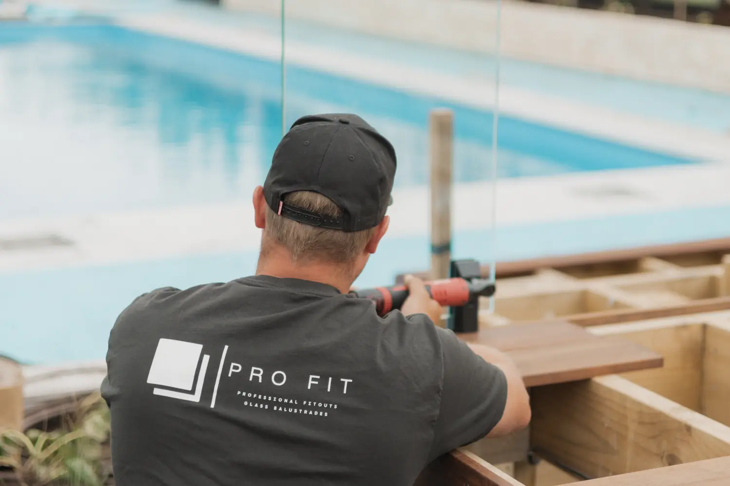 Lane installing a frameless glass balustrade beside a pool