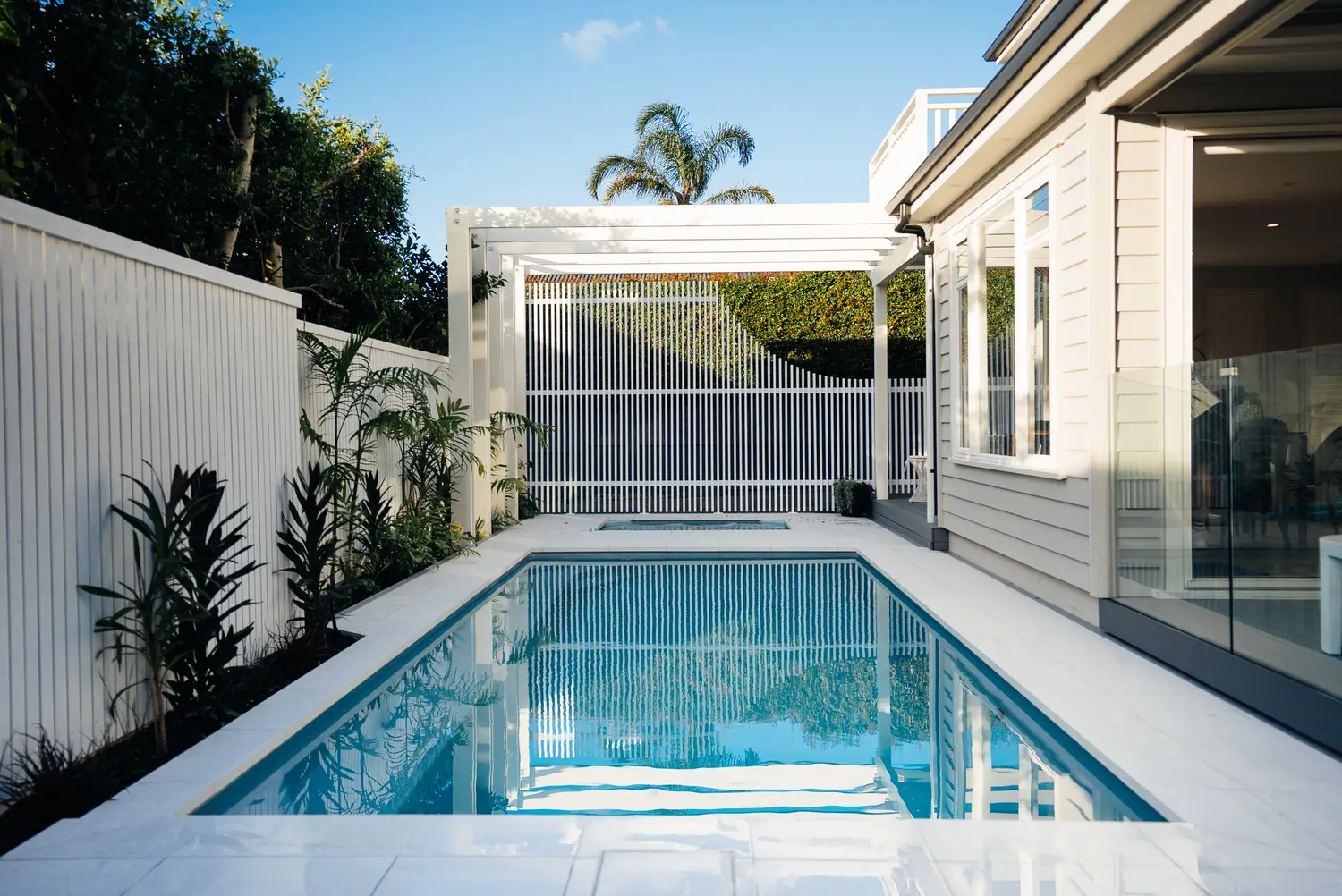 White aluminium slat screening and pool barrier around a courtyard pool