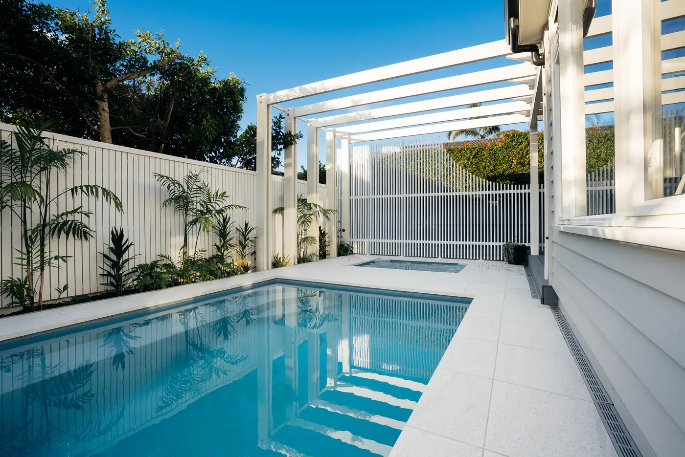 Pool with white aluminium screening and a slatted pergola