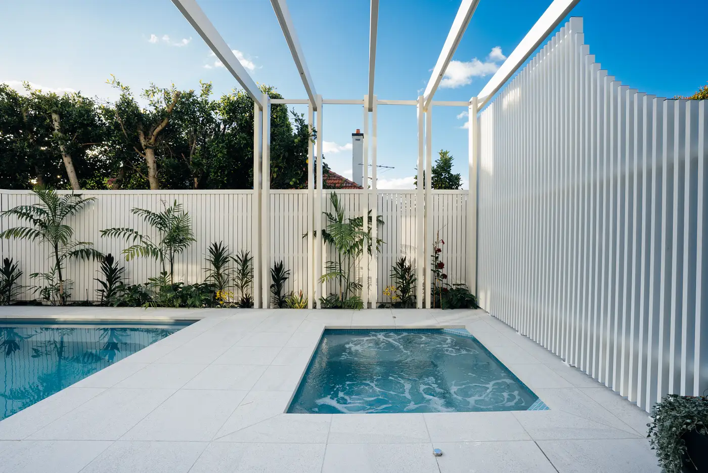 Spa and pool enclosed by white aluminium screening